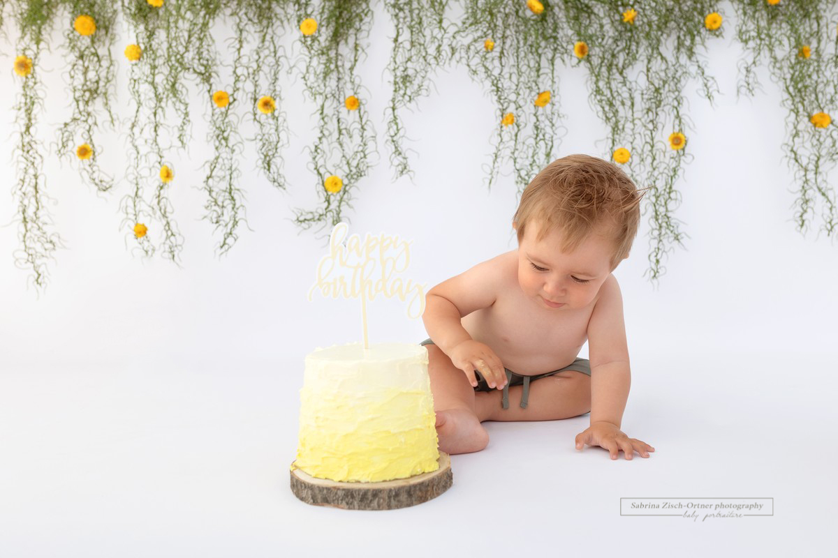 gelbe Cake Smash Torte wird beim Meilensteinshooting erkundet