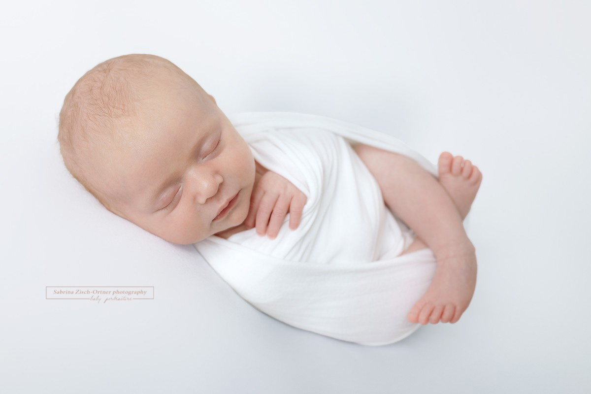 schlafendes eingewickeltes Baby beim Studio Neugeborenen Fotoshooting